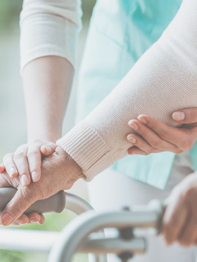 A nurse is assisting an elderly person using a walker.