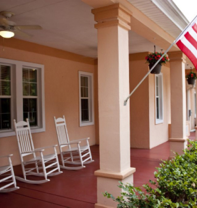 A porch with rocking chairs and an american flag.