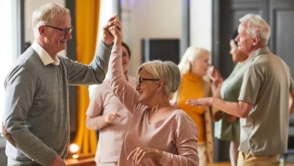 A group of older people dancing in a memory care studio.